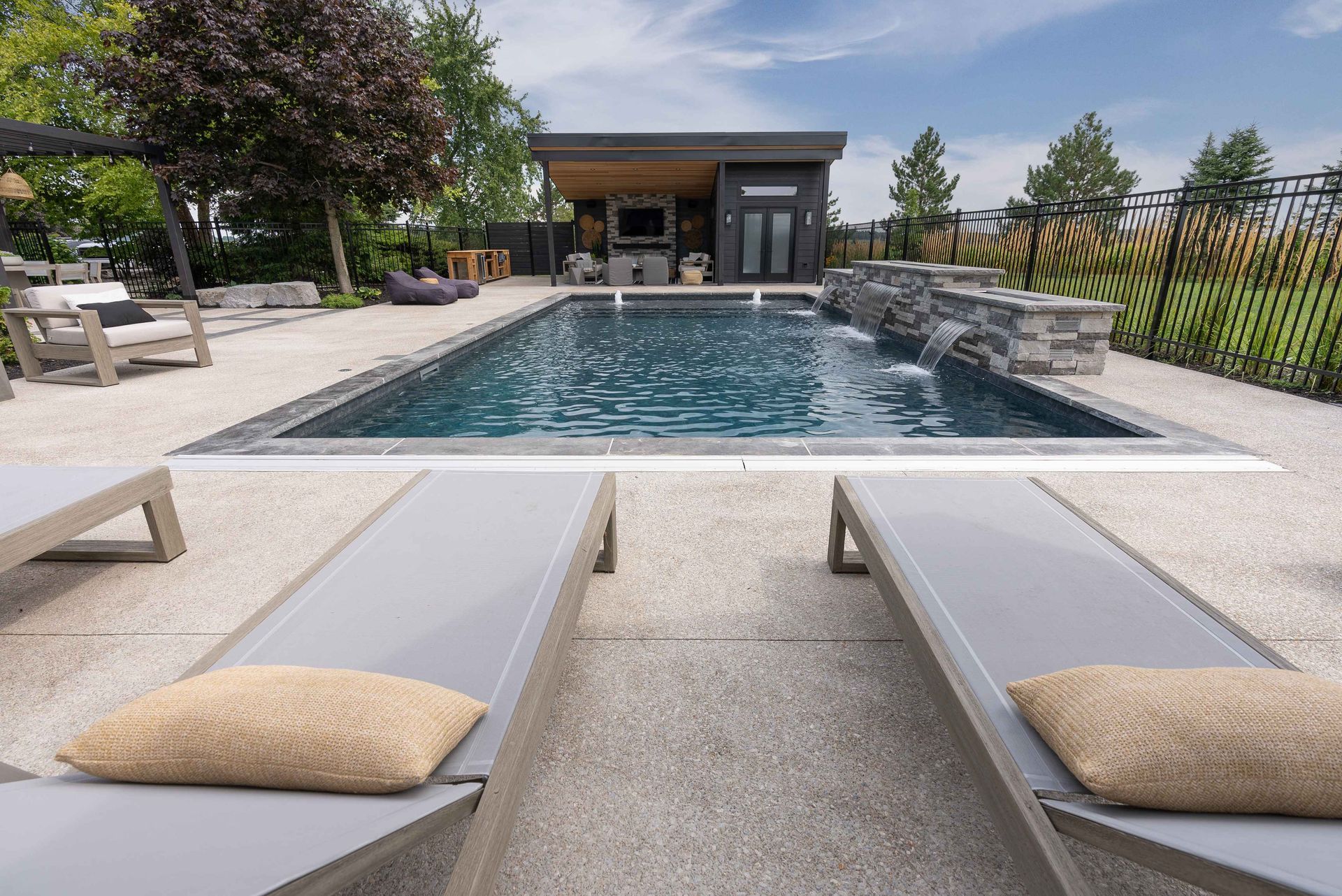 Modern poolside lounge with loungers and stone-edged swimming pool in a landscaped courtyard