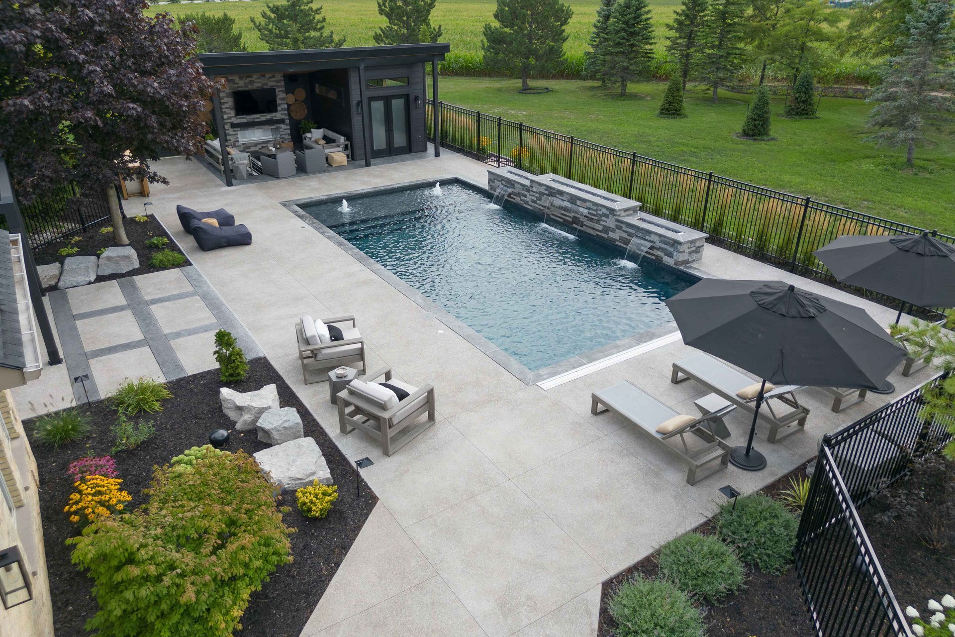 Modern backyard with rectangular pool, lounge chairs, patio seating, and a covered outdoor bar area