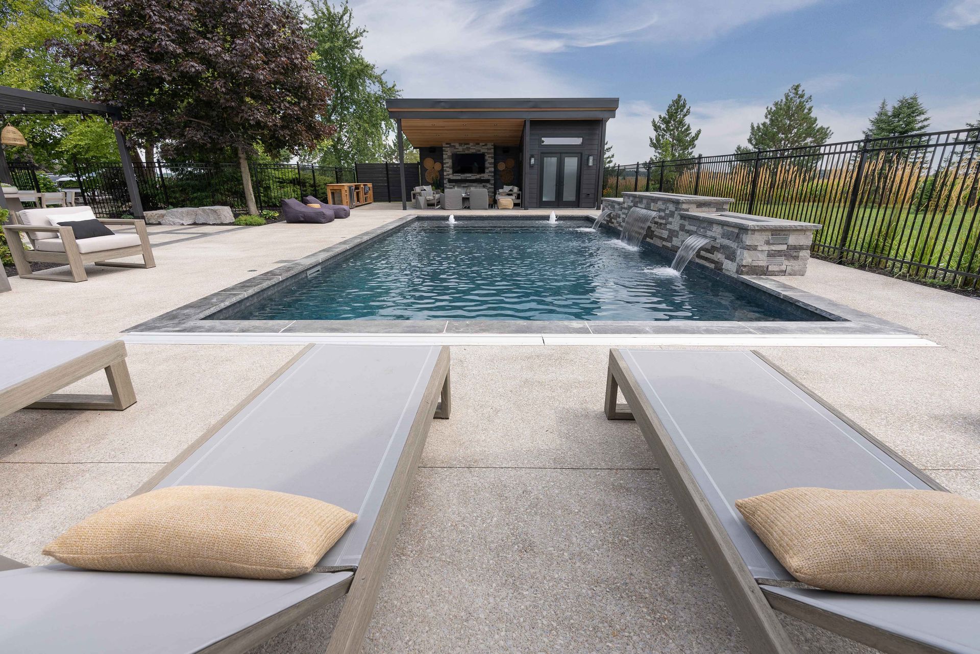 Modern outdoor pool with white lounge chairs and a cabana in the background