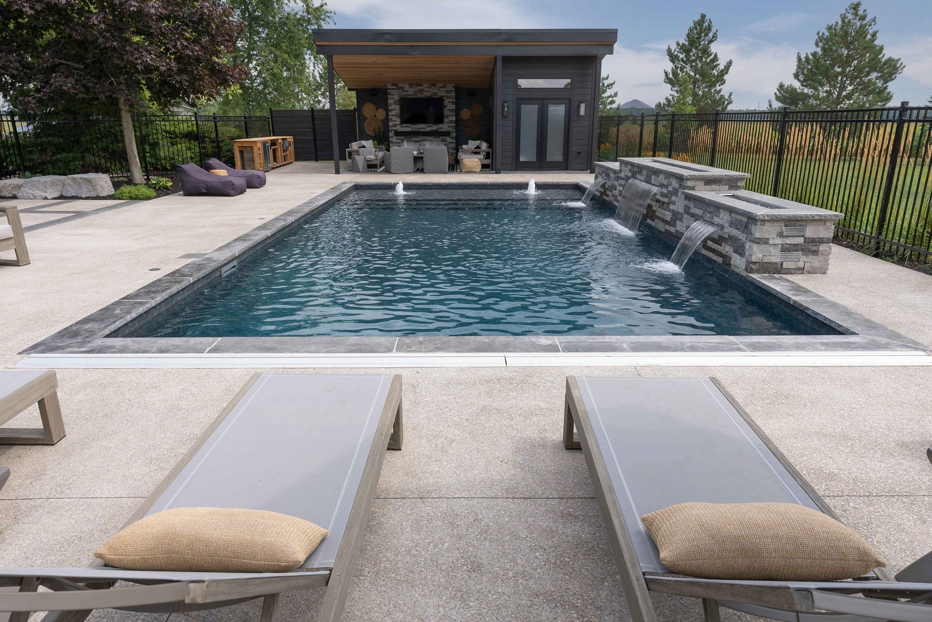 Backyard pool with stone deck, lounge chairs, and a small cabana in the background