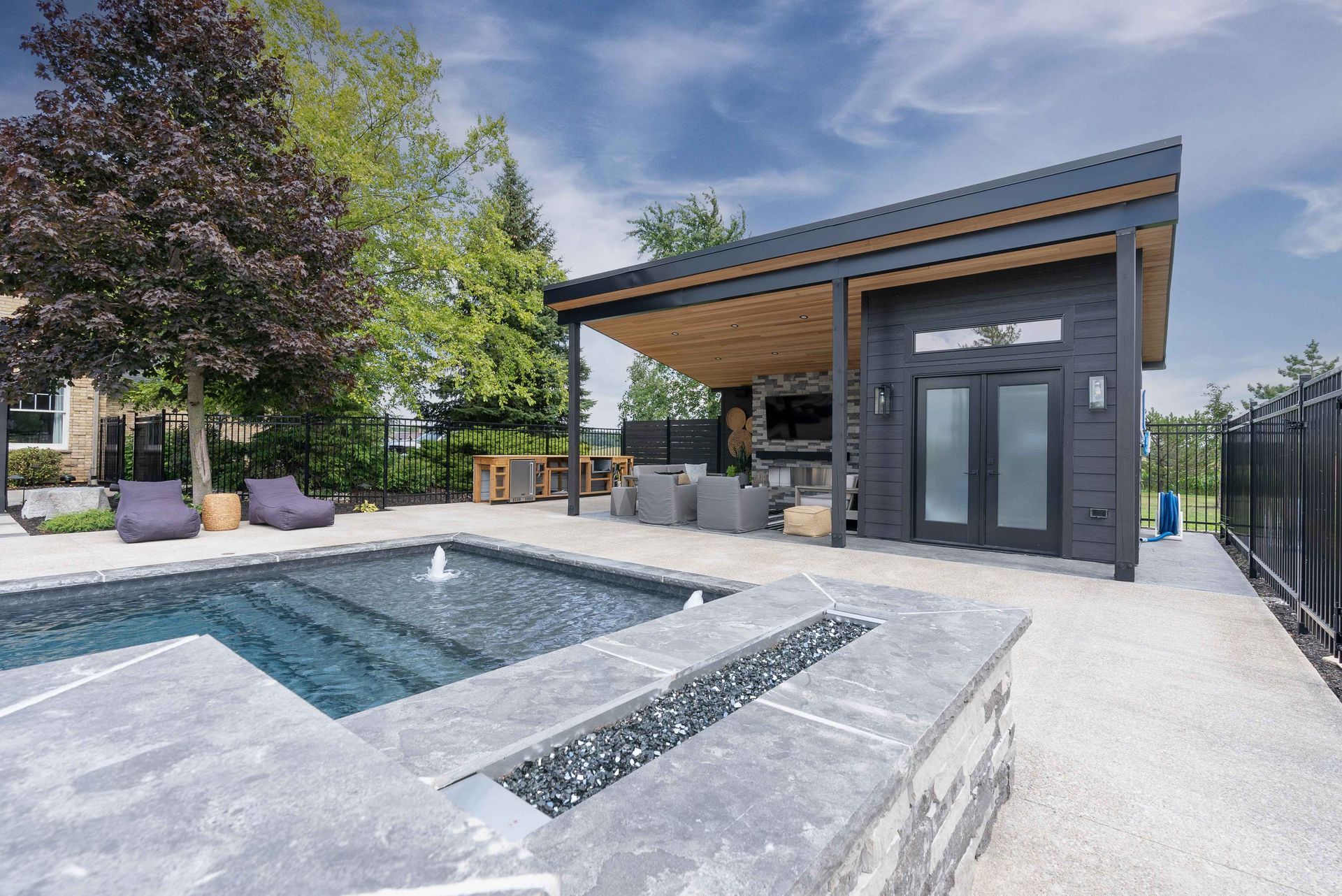 Modern backyard pool and patio with a covered outdoor lounge and fire pit.