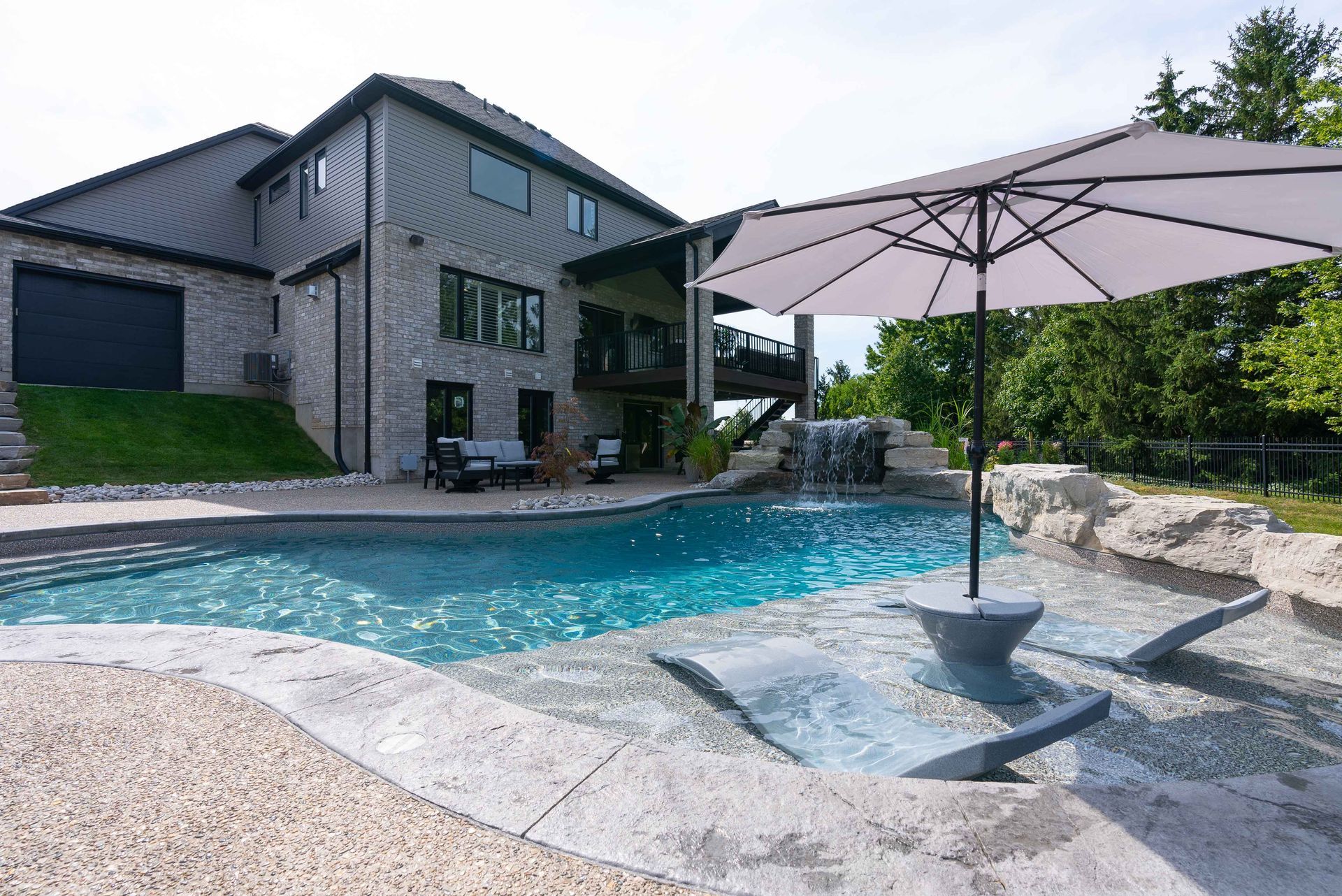 Modern house with a backyard swimming pool and patio umbrella on a sunny day