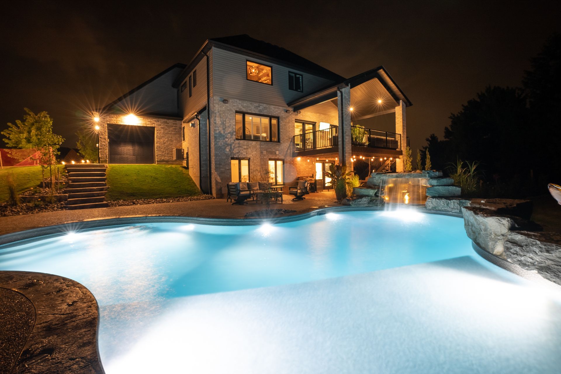Luxury house at night with glowing pool and warm exterior lights