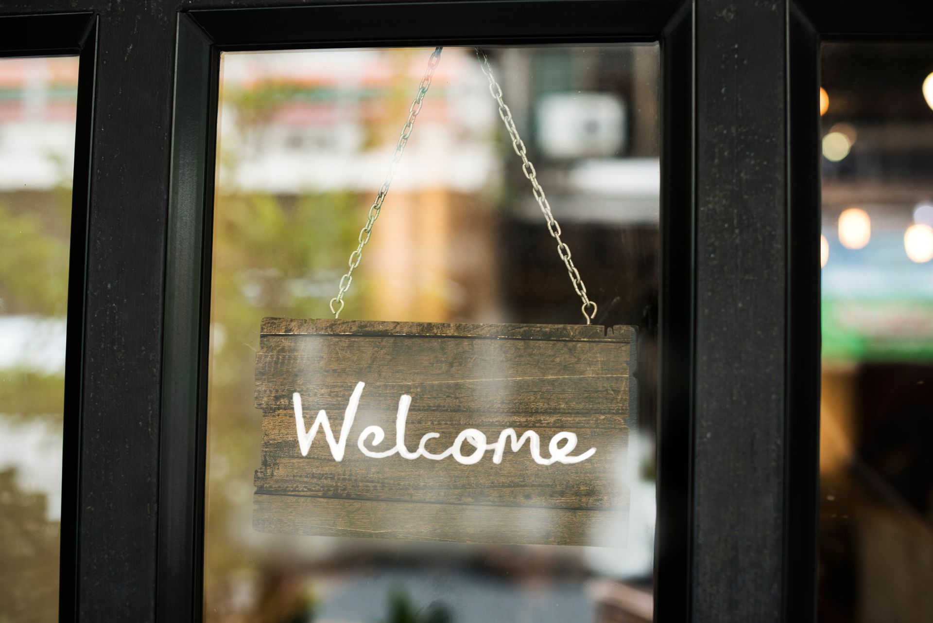 Welcome sign hanging in a glass door window