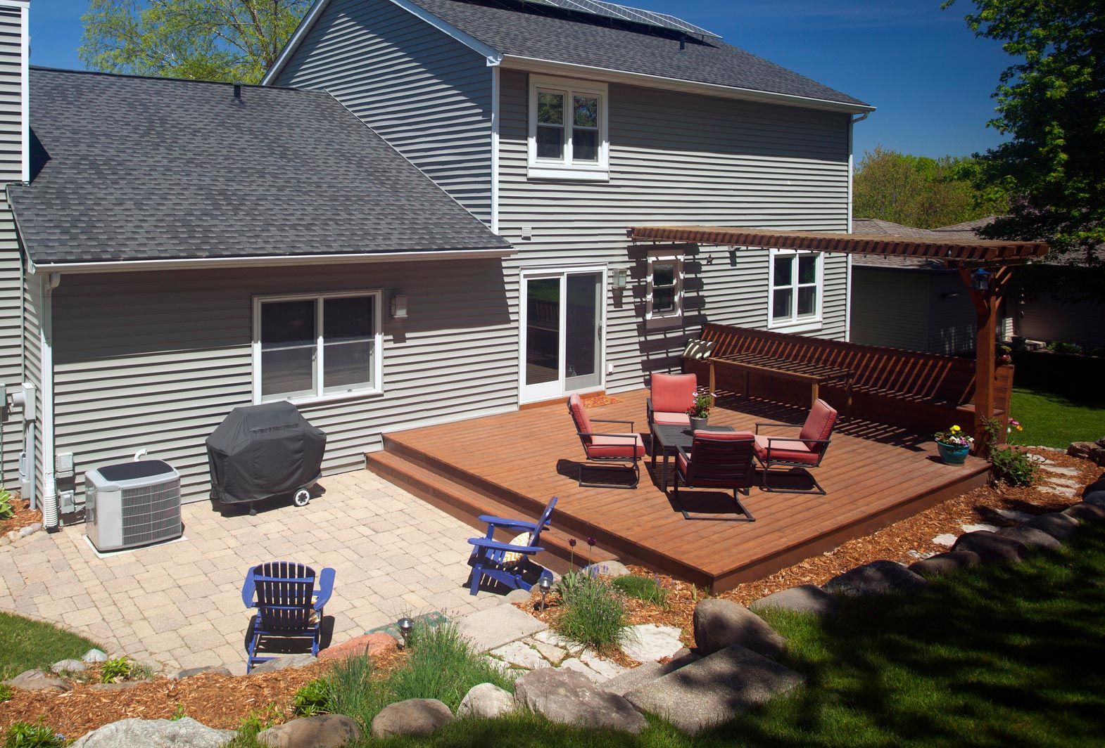 The backyard of a house with a wooden deck and chairs