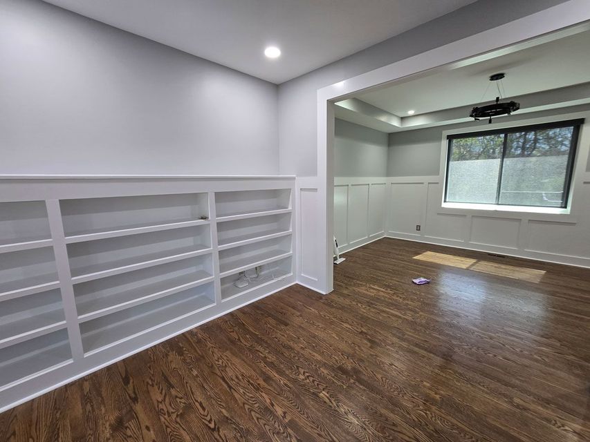 A living room with hardwood floors and white shelves.