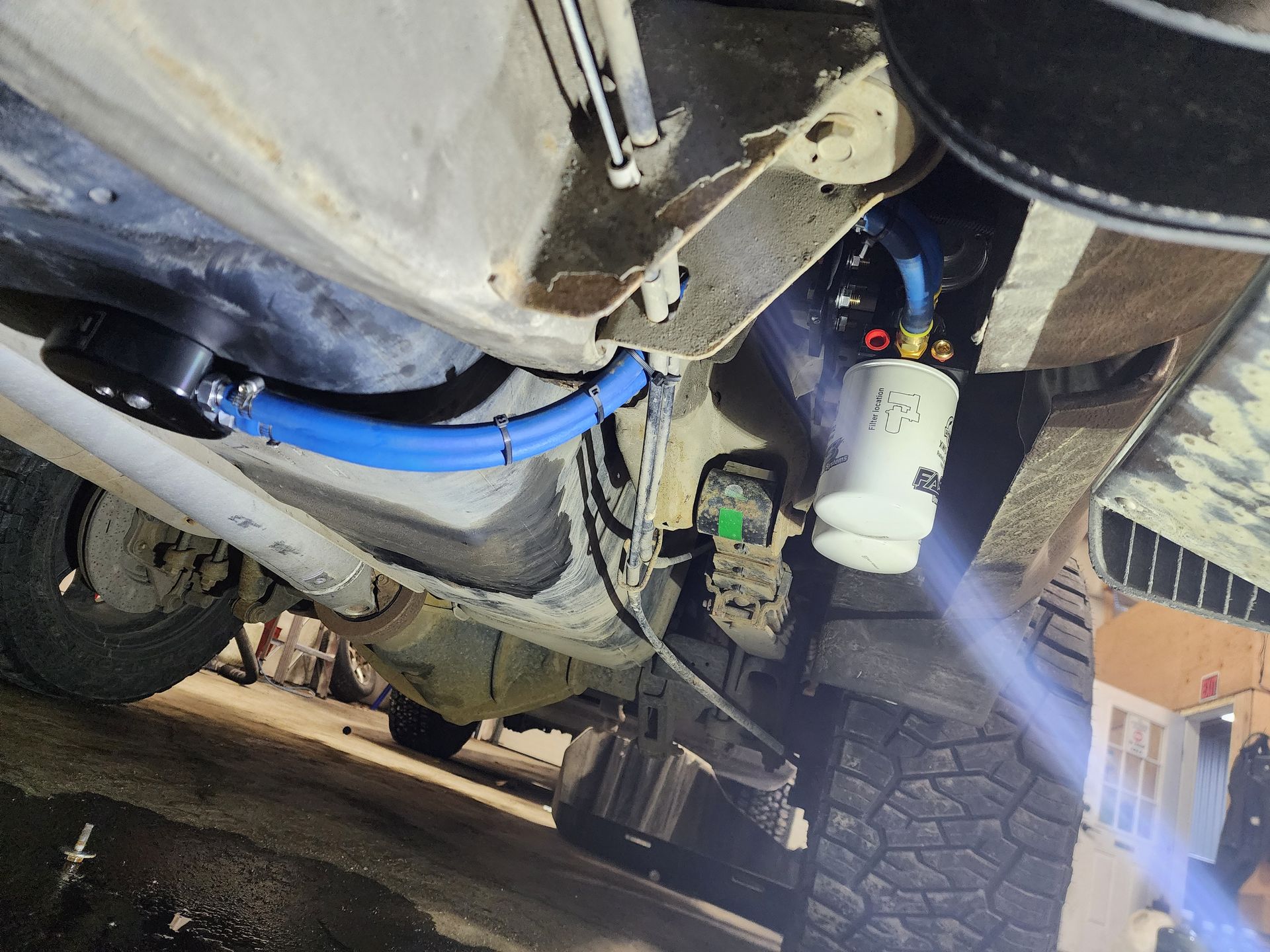 Underside of a vehicle. A blue fuel line snakes along the chassis to a white fuel filter | Alaska Diesel Repair