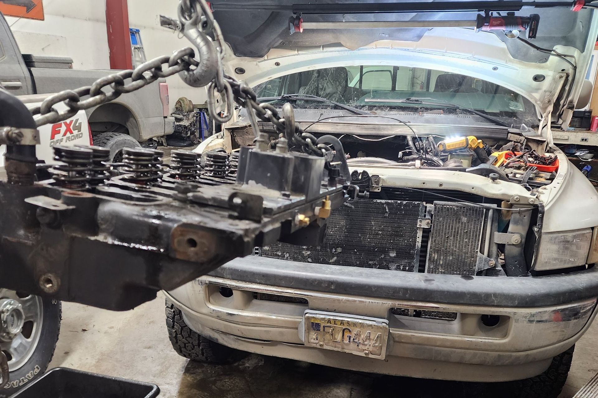 An engine being worked on in a garage; a crane is lifting engine parts | Alaska Diesel Repair