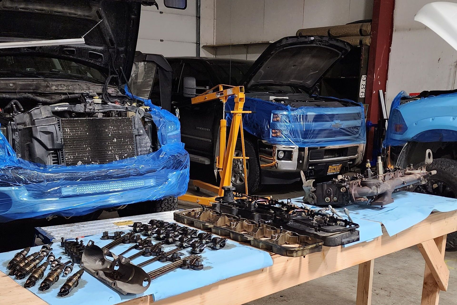 Truck repair shop with vehicles disassembled. Engines, parts on table, blue trucks | Alaska Diesel Repair