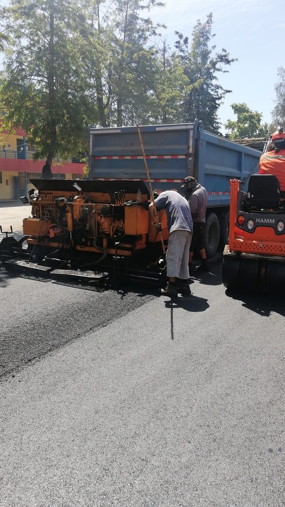 Asfaltos Patricio Contreras - Un hombre está trabajando en una carretera al lado de un camión volquete.
