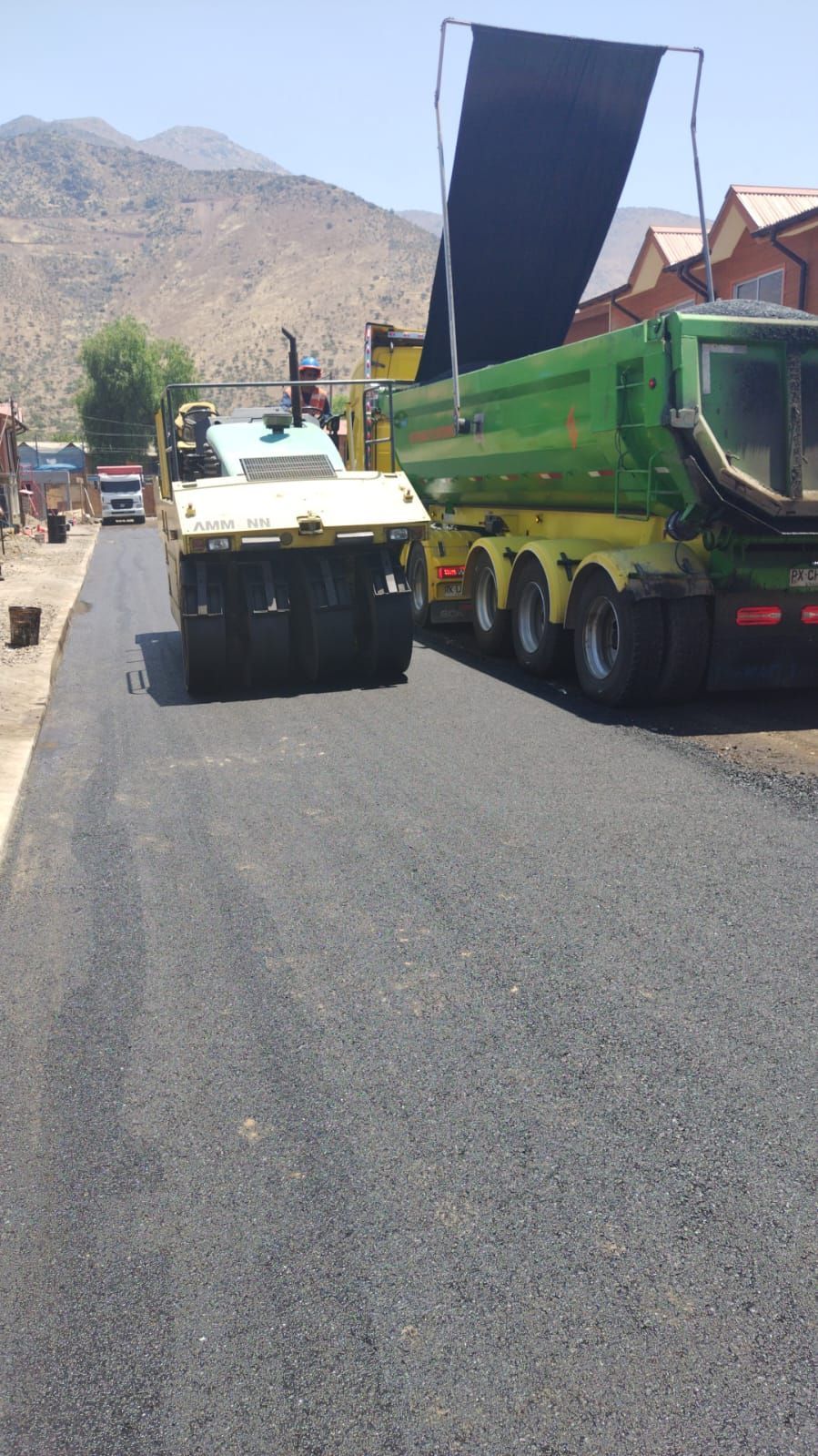 Asfaltos Patricio Contreras - Un camión de volteo circula por una carretera al lado de un rodillo.