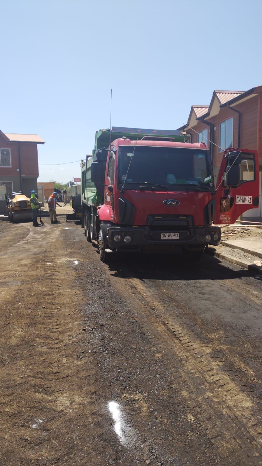 Asfaltos Patricio Contreras - Un camión rojo está estacionado al costado de un camino de tierra.