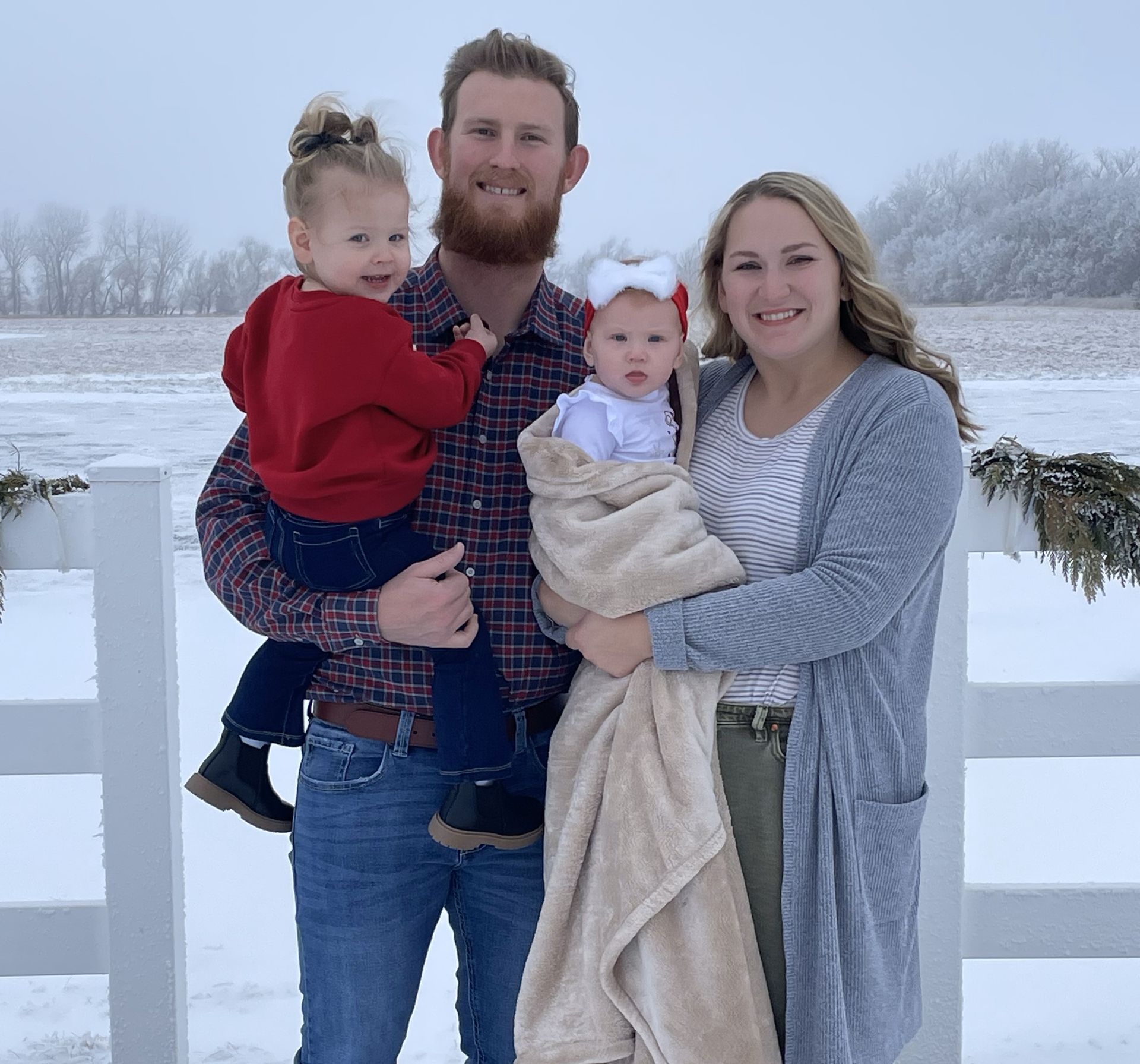 A man and woman are posing for a picture with two children in the snow.