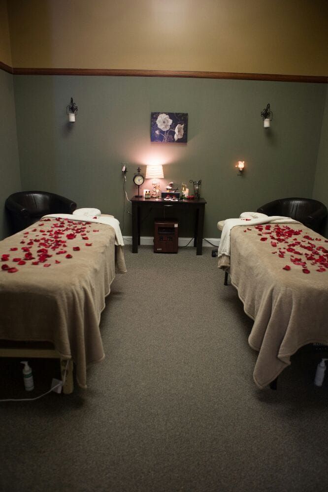 Two massage tables with rose petals on them in a room.
