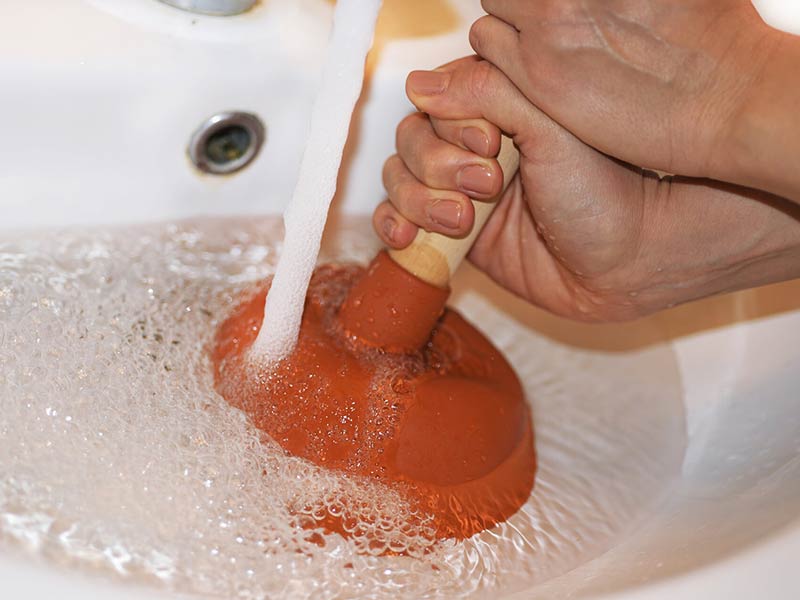 A plumber unblocking a sink in a home in Kurri Kurri