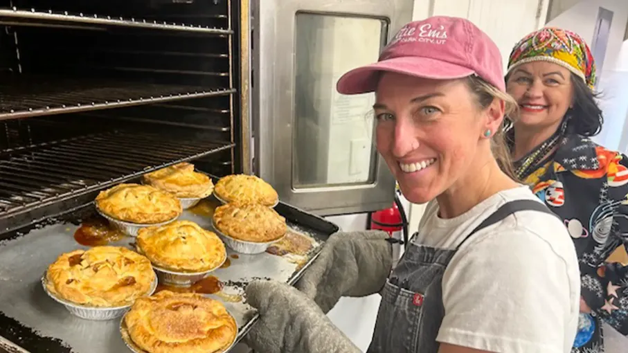 Two women are baking pies in an oven.