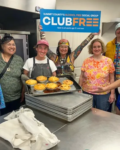 A group of people are standing around a table holding a sign that says club free.