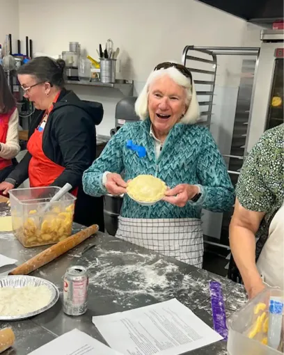 A woman is holding a piece of dough in her hands in a kitchen.