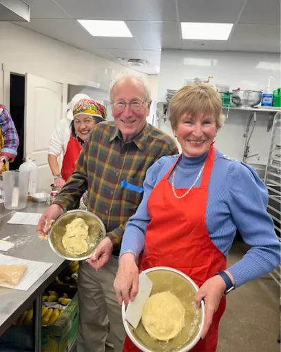 A man and a woman are holding bowls of food in a kitchen.