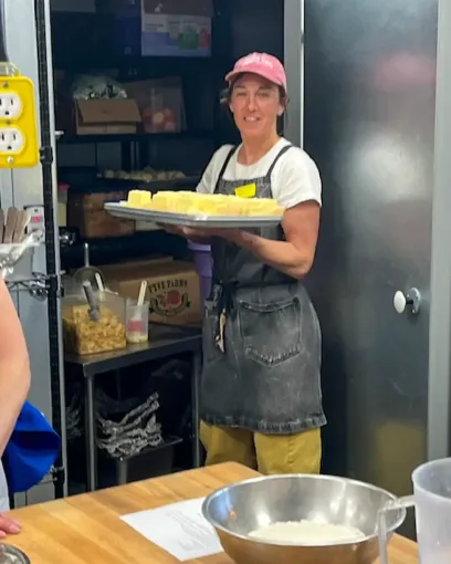 A woman holding a tray of pineapples in a kitchen
