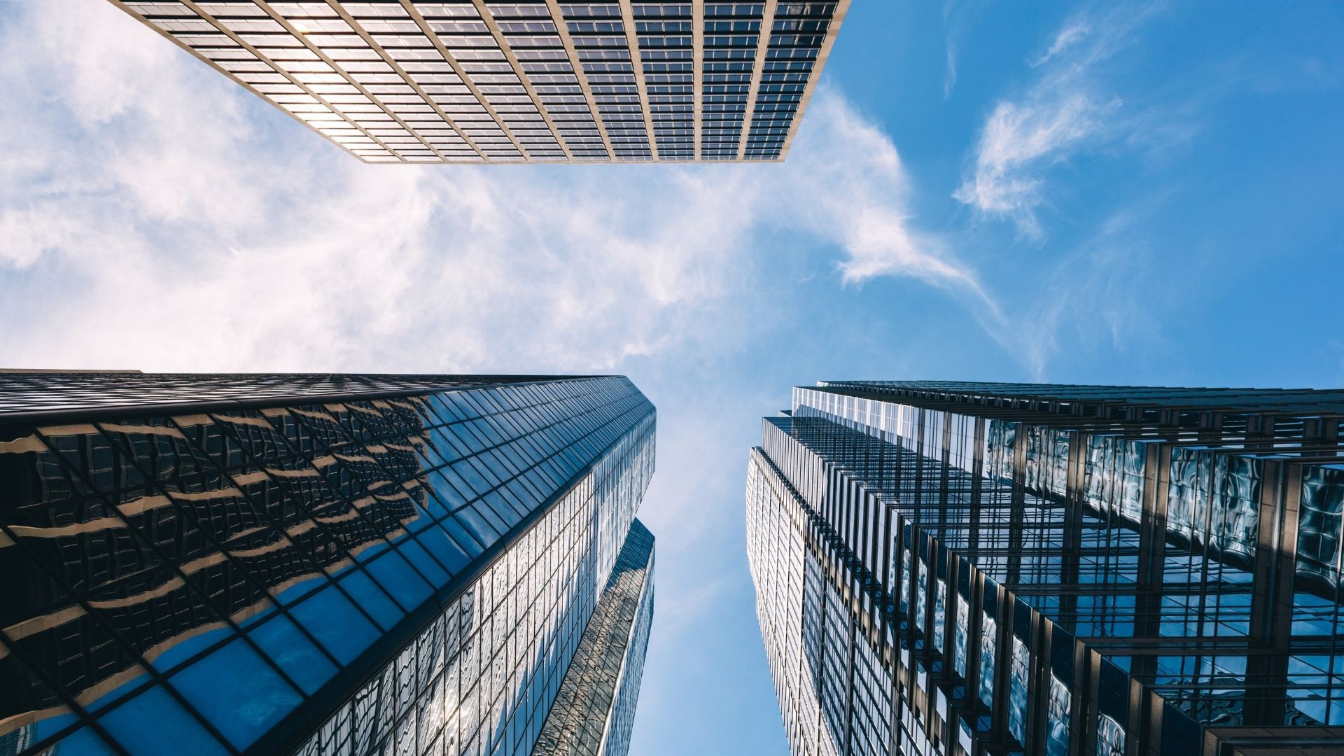 Skyscrapers viewed from below against a blue sky with scattered clouds