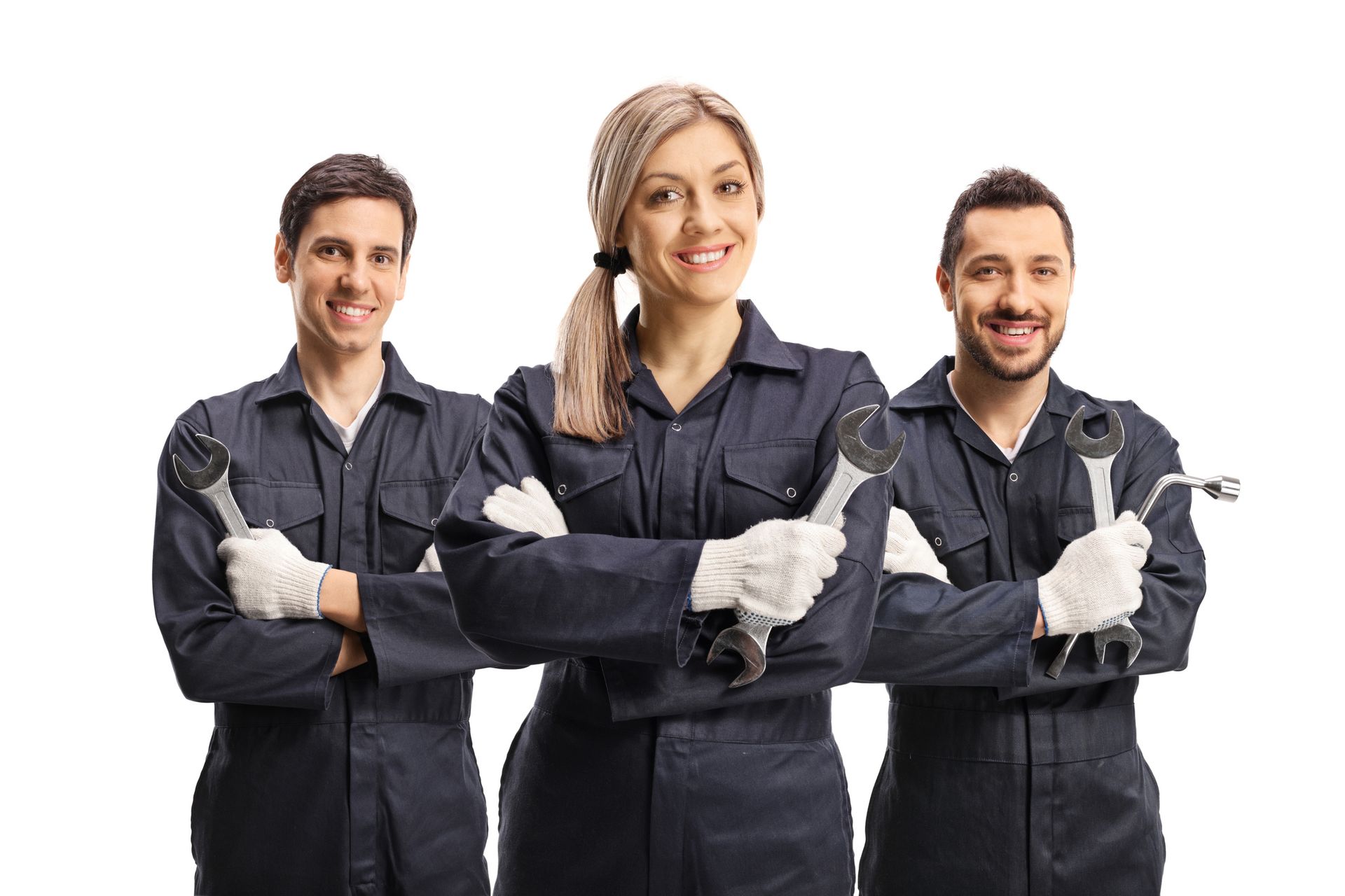 Three mechanics, two men and one woman, in blue jumpsuits, holding wrenches, smiling.
