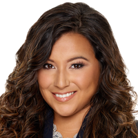 Woman with long brown curly hair smiles.