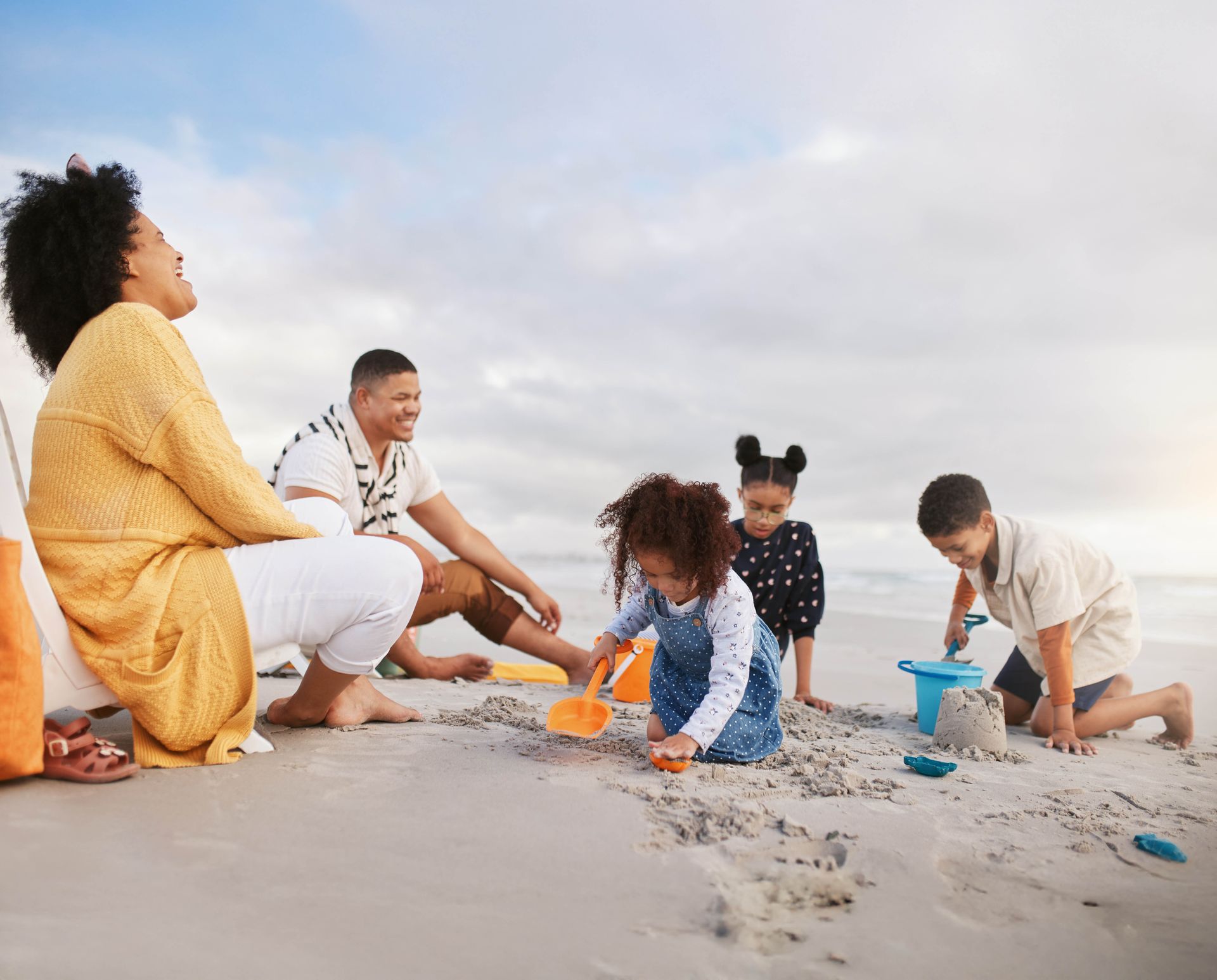 Family of five enjoying a sunny beach day, playing in the sand, laughing.