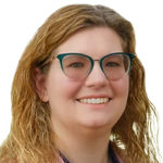 Woman with blonde hair and teal glasses smiling.