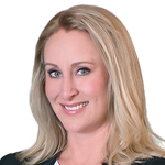 Woman with blonde hair smiles, wearing dark jacket, blue eyes.