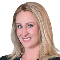 Woman with blonde hair smiles, wearing dark jacket, blue eyes.