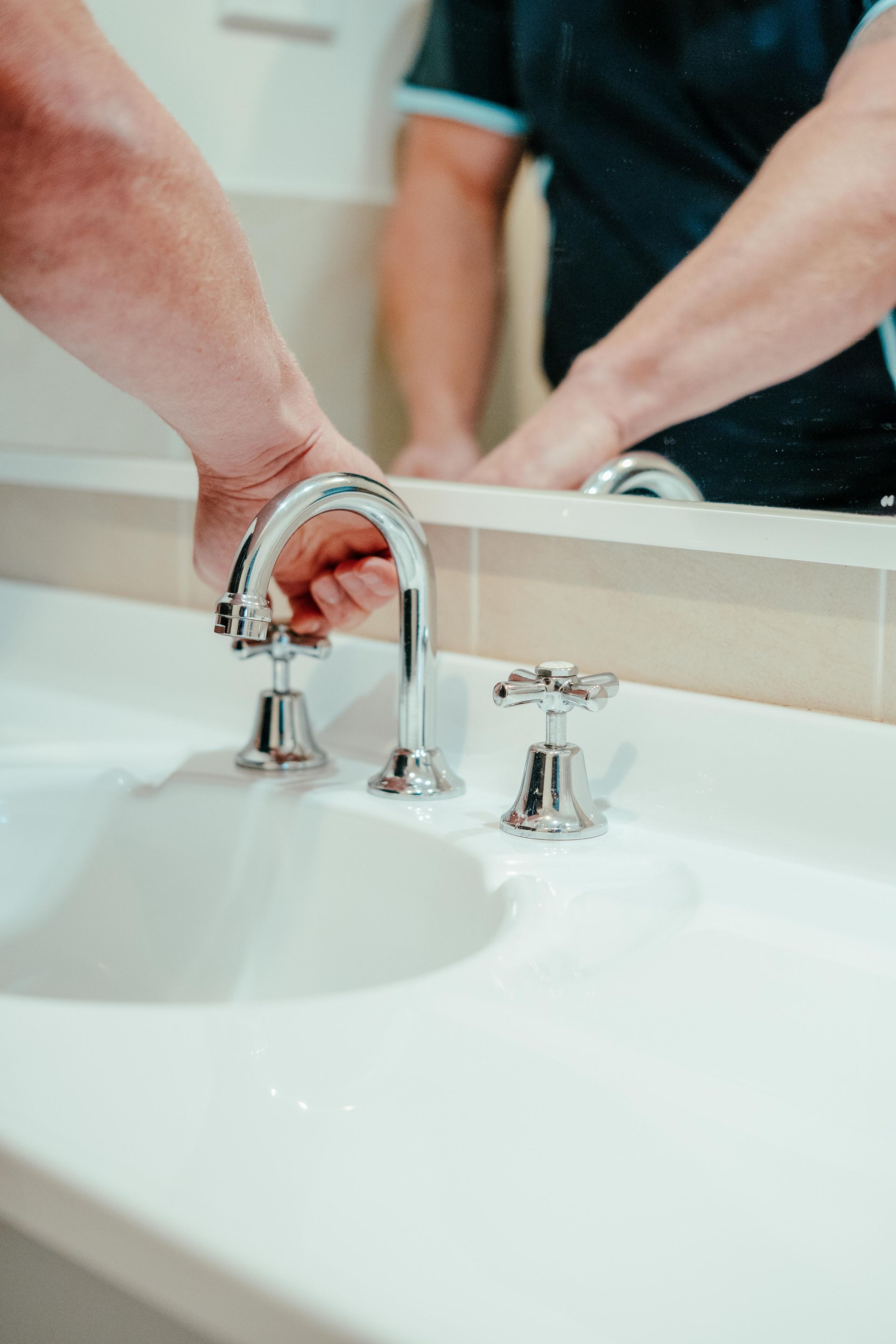 Hands washing under a chrome faucet at a bathroom sink — Aquafix Plumbing Services in Bowral, NSW