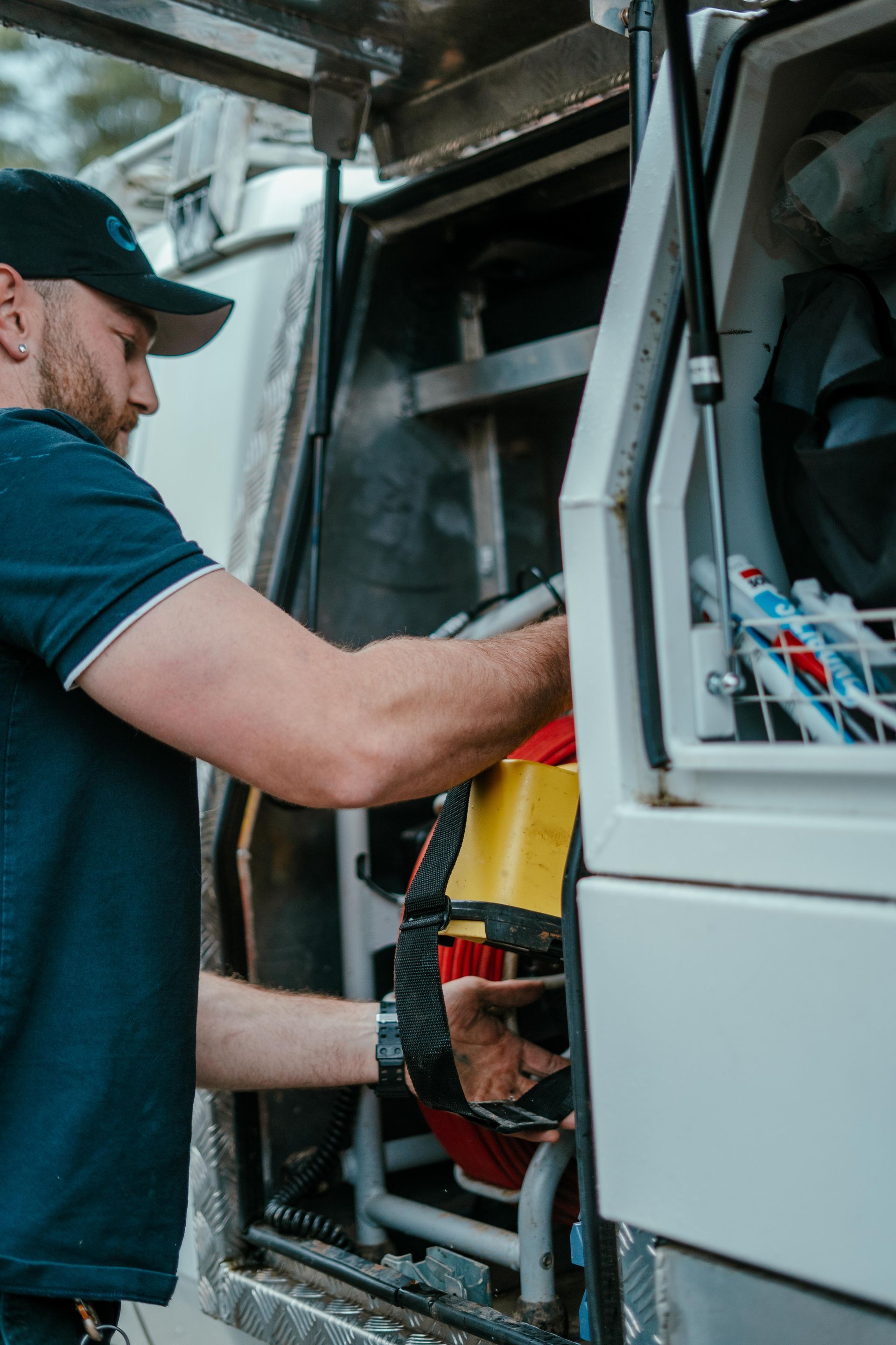 Technician working inside a service van, handling equipment with open compartments. — Aquafix Plumbing Services in Bowral, NSW