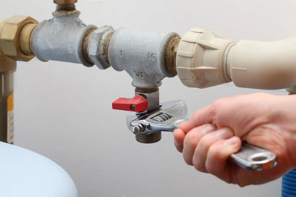 A Person Is Fixing A Pipe With A Wrench — Aquafix Plumbing Services in Bowral, NSW