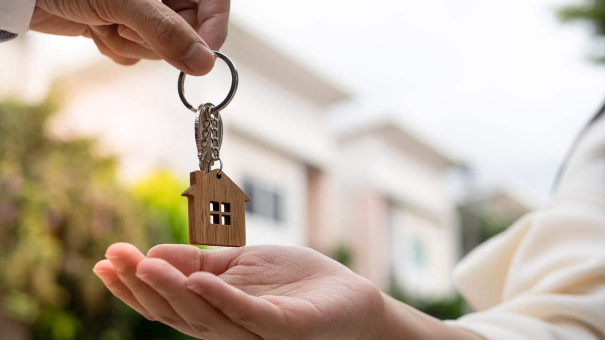 A person is handing a house key to another person.