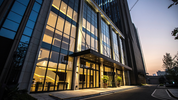 Modern building with glass windows, entrance, and dusk sky.