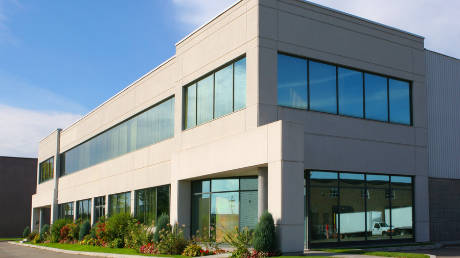 Modern two-story building with large windows and a clear blue sky.