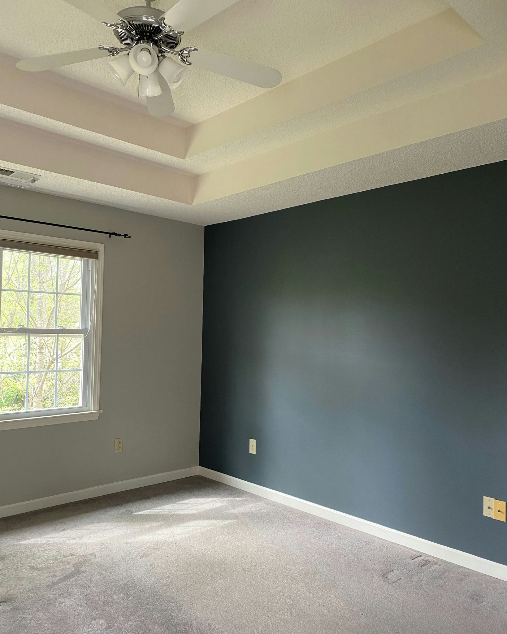 Bedroom with gray and blue walls, window, and ceiling fan.