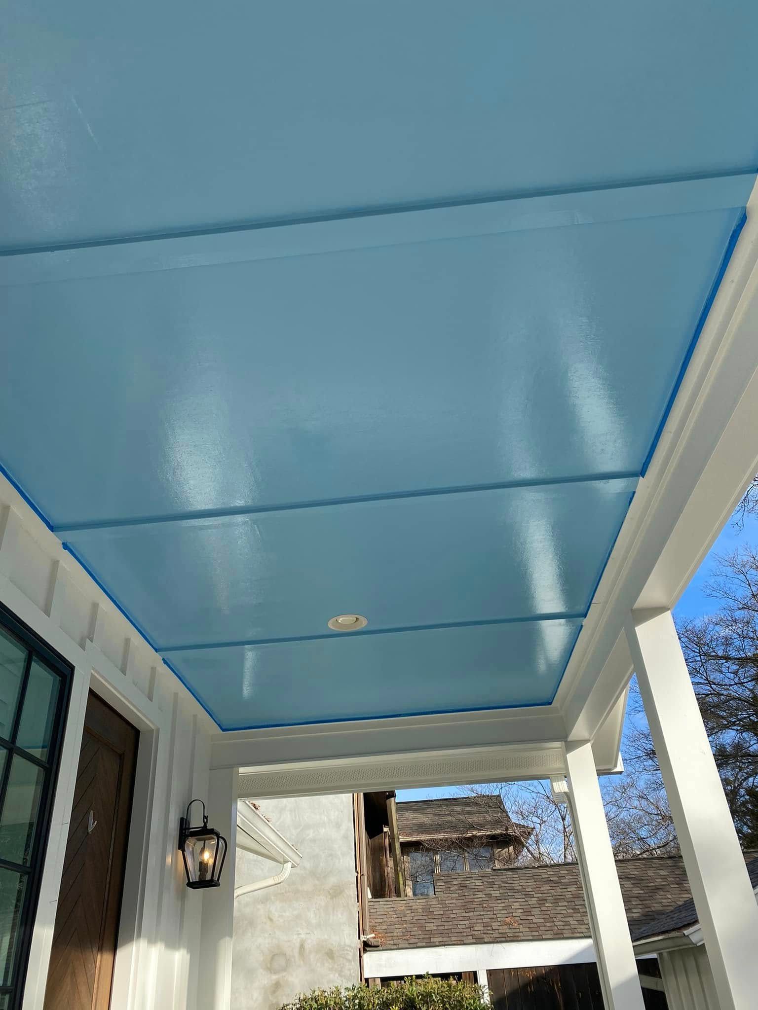 Blue painted porch ceiling with white trim and a light fixture.