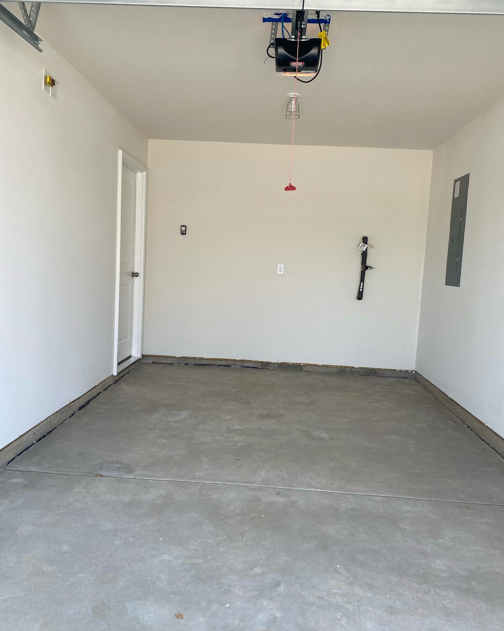 Empty garage interior with white walls and a gray concrete floor.