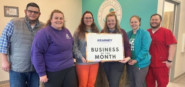 A group of people standing next to each other holding a sign that says business of the month.