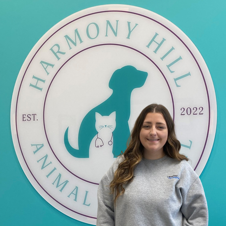 A woman stands in front of a sign for harmony hill animal hospital