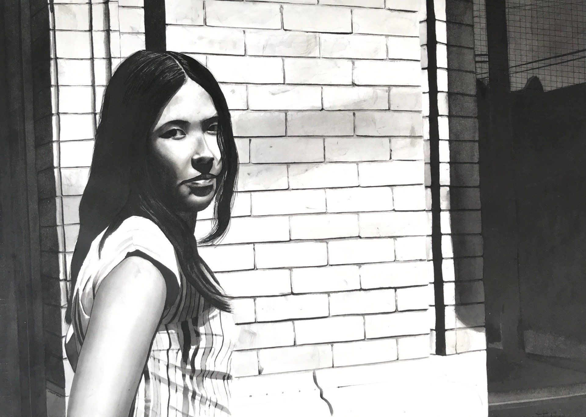 A black and white photo of a woman standing in front of a brick wall