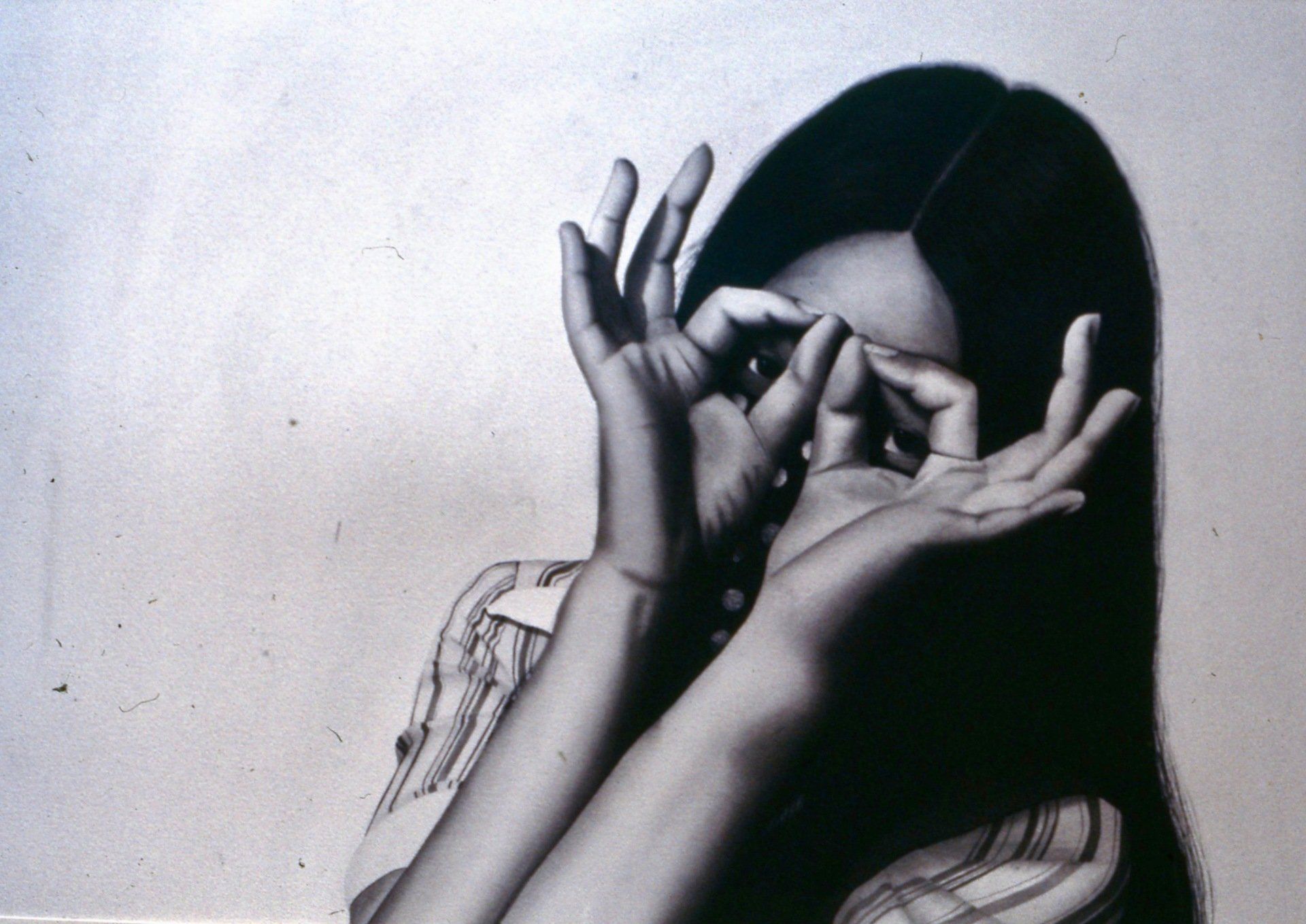 A woman covering her face with her hands in a black and white photo