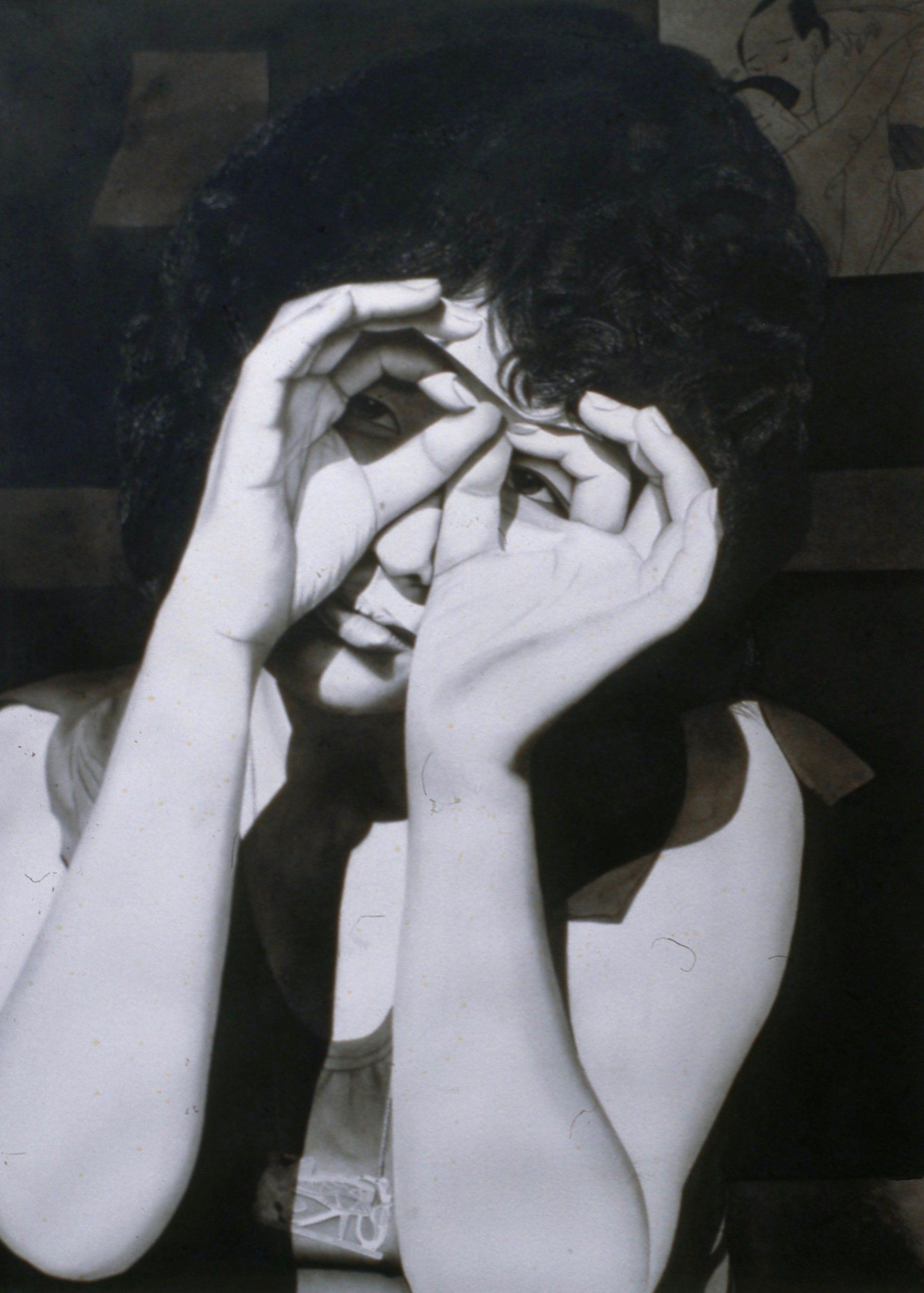 A black and white photo of a woman covering her face with her hands