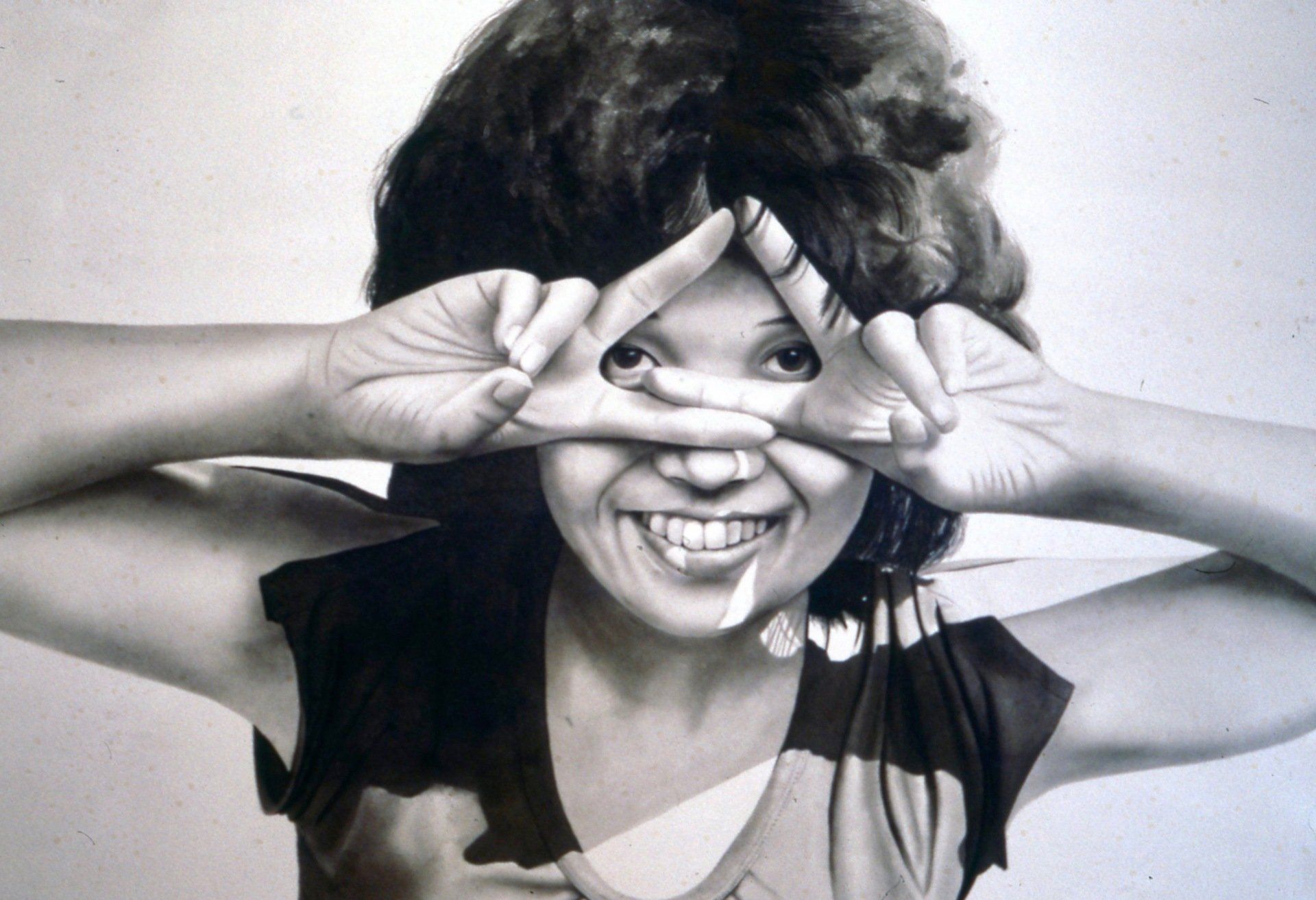 A woman covering her eyes with her hands and smiling