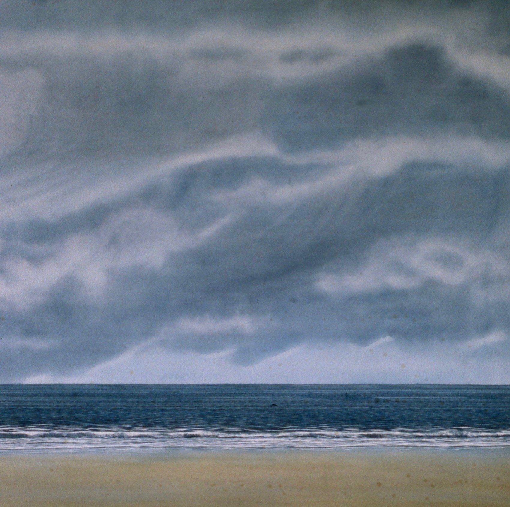 A beach with a cloudy sky in the background