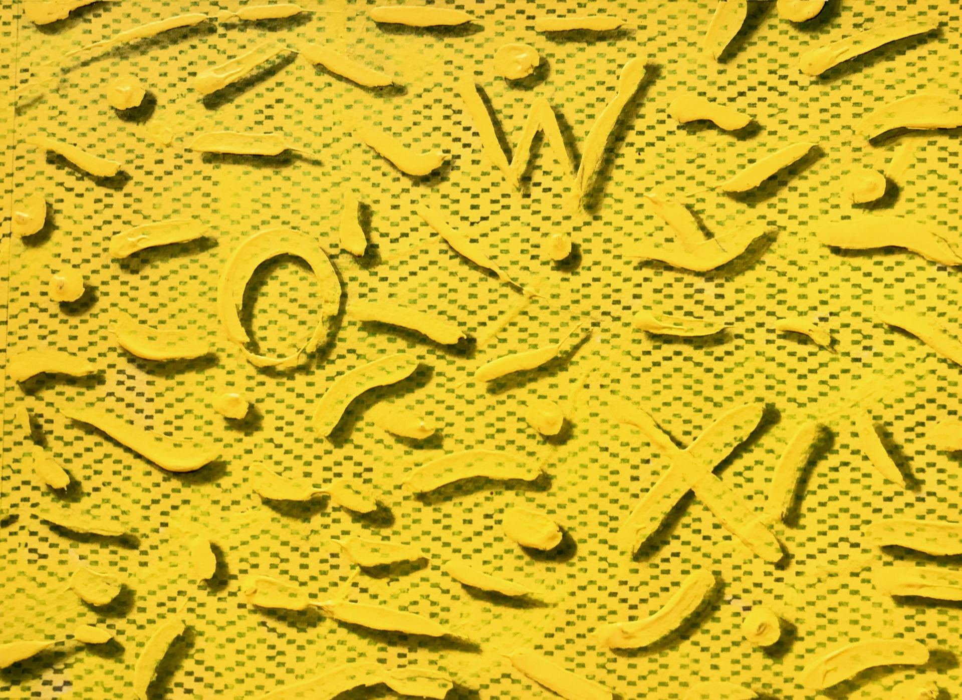 A close up of a yellow surface with a pattern of letters on it.