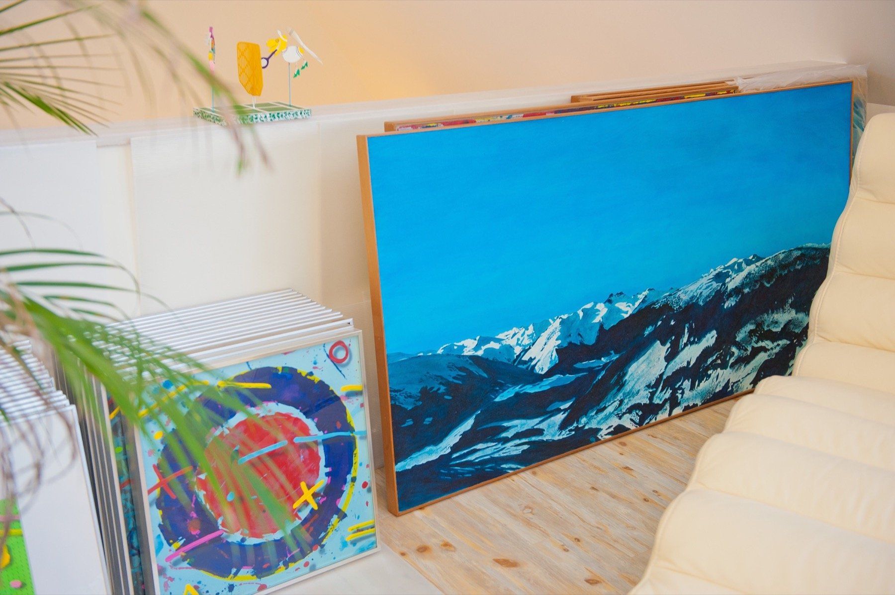 A large painting of a landscape is hanging on a wall next to a couch.