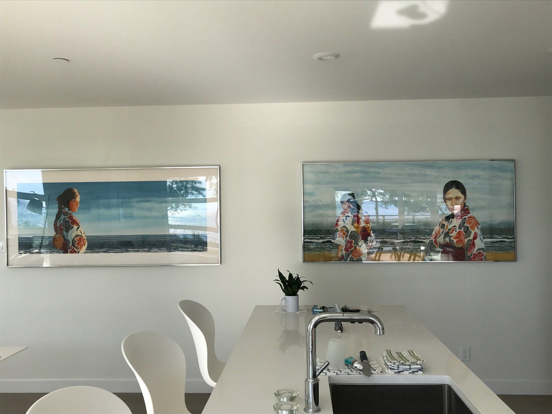 A kitchen with a sink and two paintings on the wall
